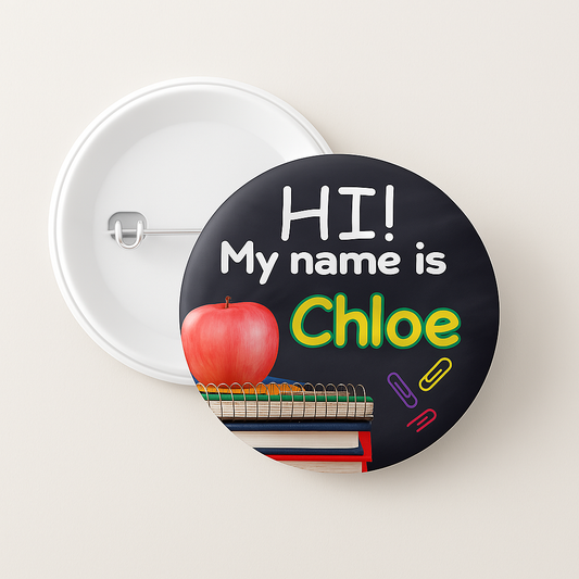 Name tag button with 'HI! My name is Chloe' text, apple, books, and paper clips on a black background.